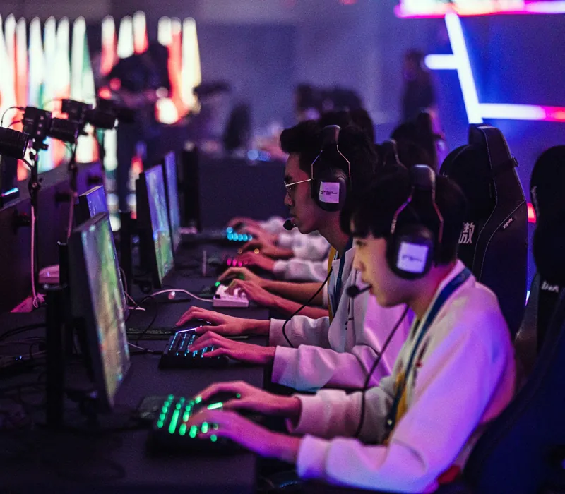 Jugadores de esports con auriculares compitiendo en una sala con luces de neón